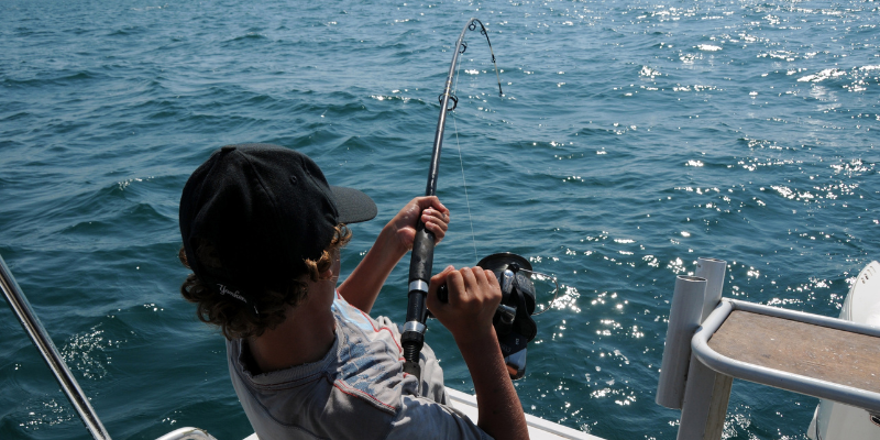 Man reeling in a fish on the open ocean.