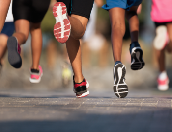 Image of the feet of multiple people running across pavement.