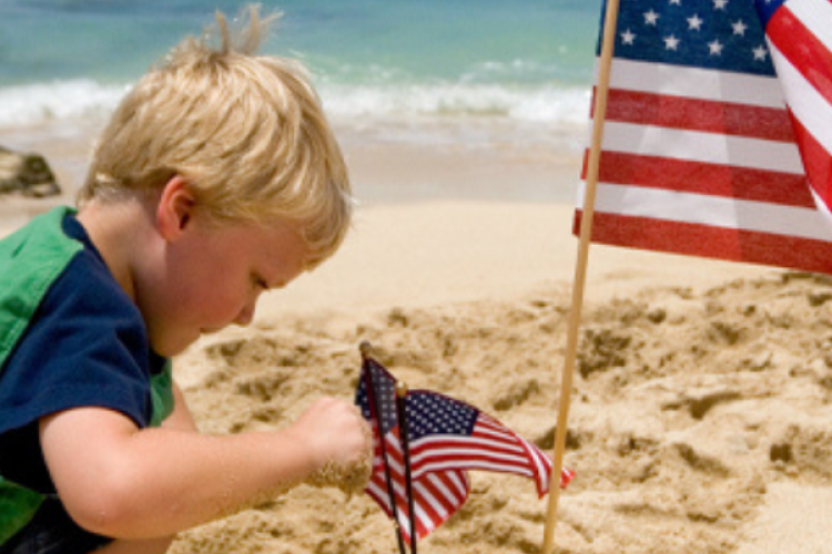 Child building a sand castle on the Outer Banks. Ocean in the background.