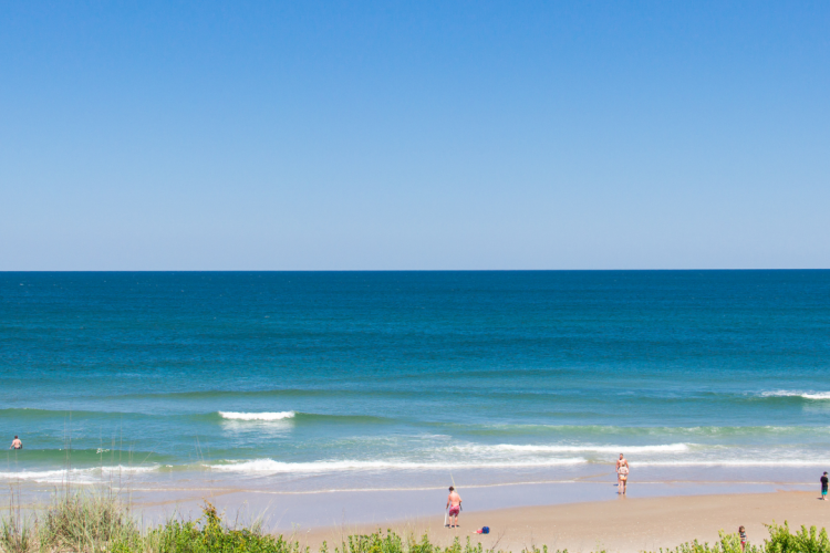 Pretty summer beach day on the Outer Banks. View of the aqua ocean and sandy shoreline.