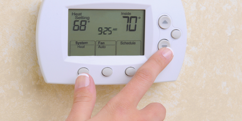 Manicured hand changing temperature on thermostat.