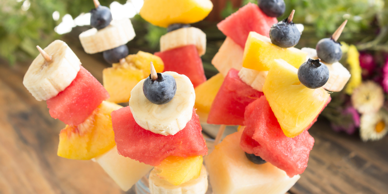Beach Snacks - Fresh Fruit Skewers; Image of watermelon, peaches, bananas, and blueberries on wooden sticks.