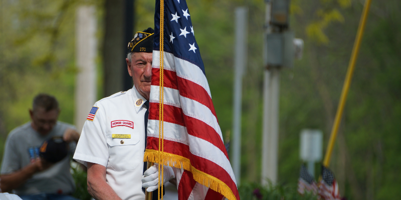 Honor Guard member standing behind American Flag