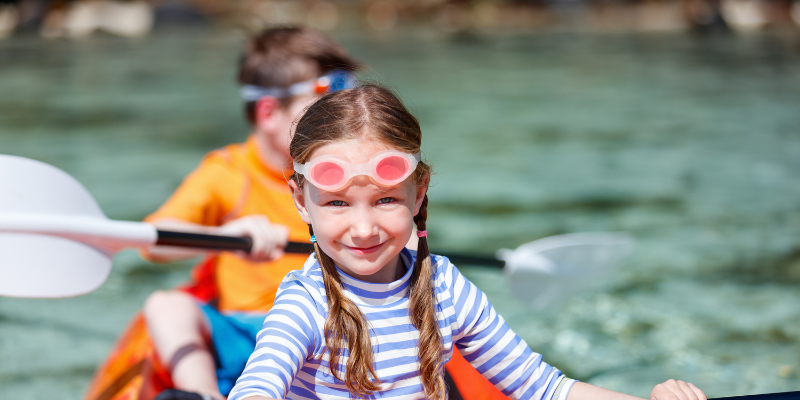 Close up of a girl in a striped shirt kayaking with her brother.