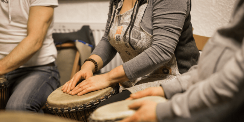 Three people using hand drums.