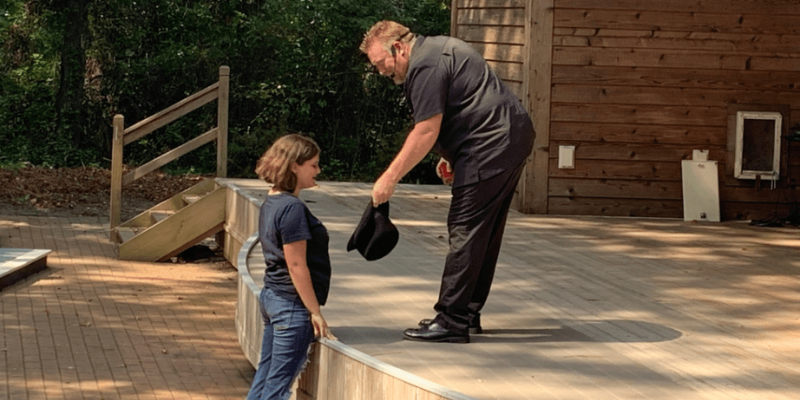 Magician showing child inside of a black hat.