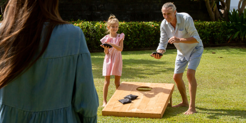 Corolla Cornhole Tournaments Man and child playing cornhole.