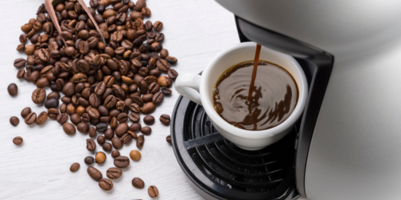 Image of coffee maker from above with coffee beans on the counter.