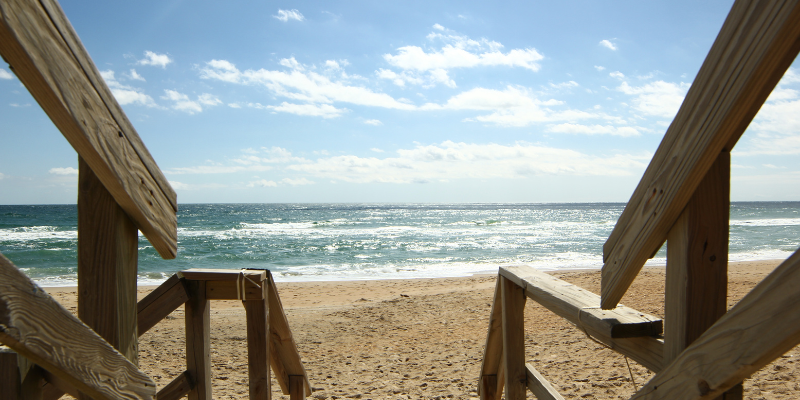 Image shows frame of a wooden deck/beach access onto the sand.