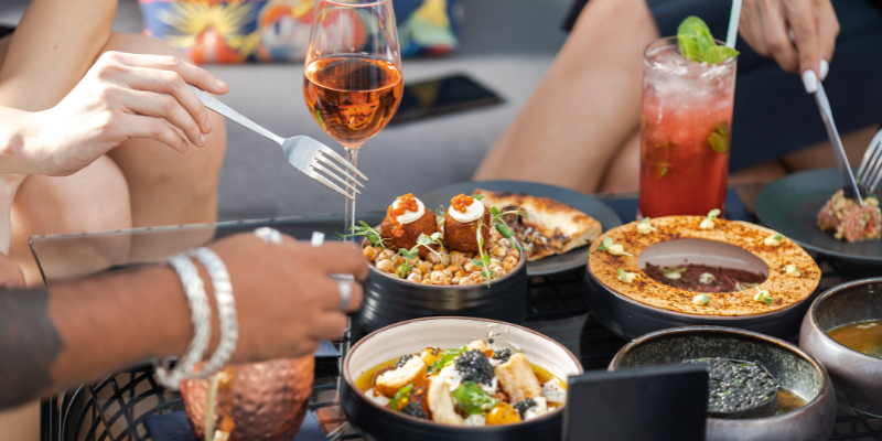 Image of bowls of food and wine glasses shared between three people.