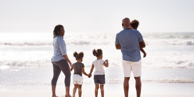 African American family walking away from the camera on the beach.