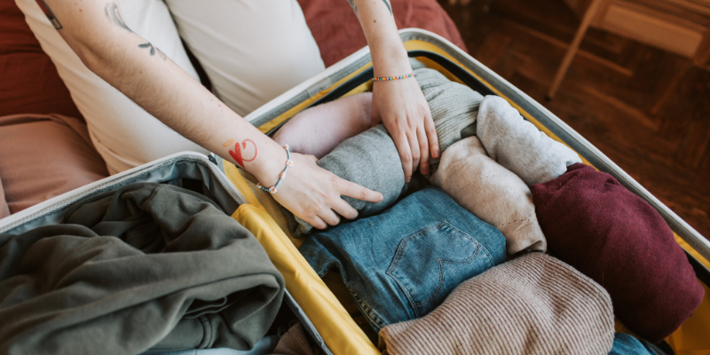 Image of someone filling a suitcase with rolled clothes.