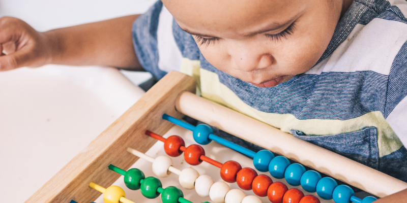 Toddler playing with abacus.