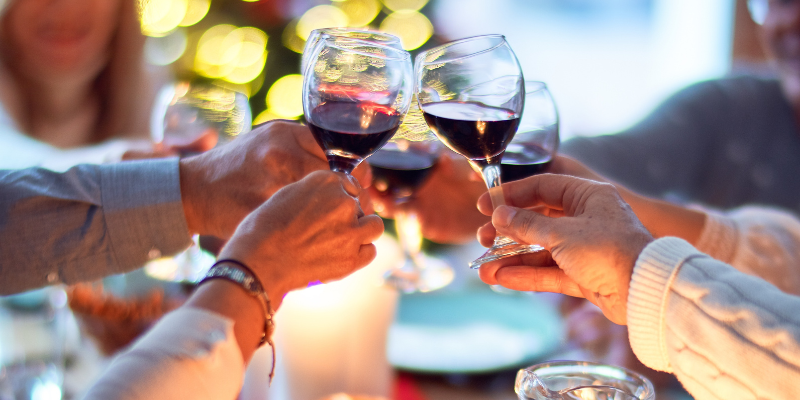 Image of four people toasting wine glasses in the center of a table.