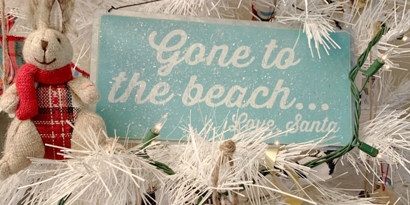 White Christmas tree with blue sign that reads "Gone to the Beach, Love Santa"