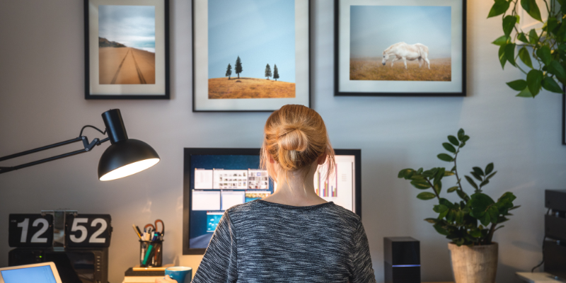 Office with a woman working and landscape paintings on the wall.